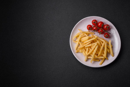 Fresh delicious crispy French fries with salt and spices on a dark concrete background