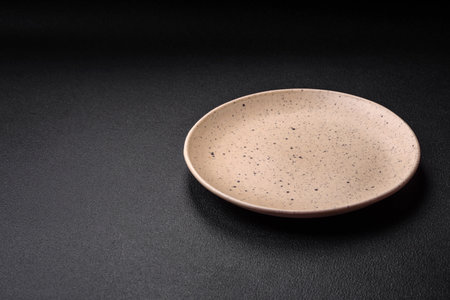 Empty ceramic plate on a dark textured background. Preparing kitchen utensils for a family dinnerの写真素材