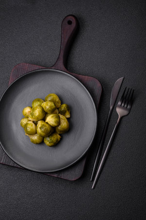 Delicious boiled Brussels sprouts on a ceramic plate on a dark concrete background. Vegetarian foodの写真素材