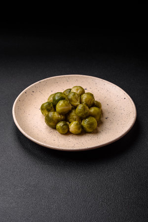 Delicious boiled Brussels sprouts on a ceramic plate on a dark concrete background. Vegetarian foodの写真素材