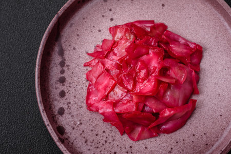 Delicious spicy pink cabbage sliced and cooked in Korean style on a ceramic plate on a dark concrete backgroundの写真素材