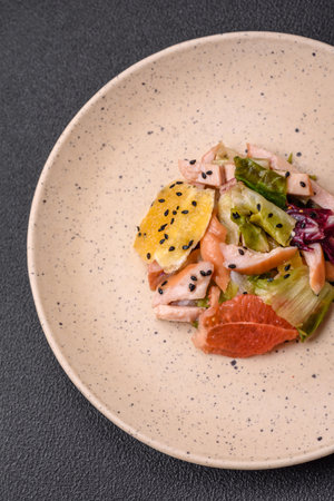 Delicious fresh juicy salad of sliced chicken, grapefruit, lettuce, sesame with olive oil on a ceramic plate on a concrete backgroundの写真素材
