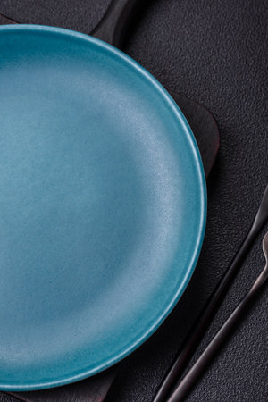 Beautiful empty round ceramic plate on a concrete background. Kitchen utensils for serving food on...