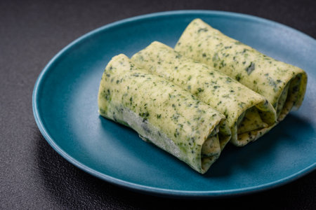 Delicious fresh pancakes with spinach, cream cheese, salmon, salt and spices on a dark concrete...