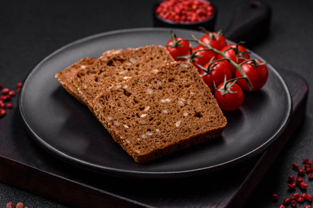 Delicious fresh crispy brown bread with seeds and grains on a dark concrete backgroundの写真素材