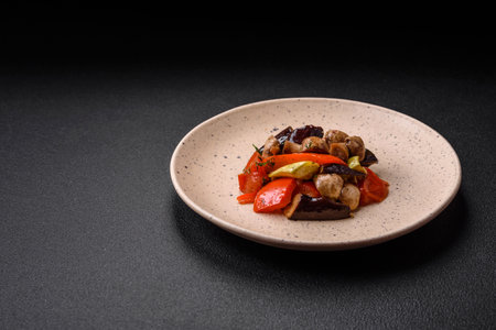 Delicious salad of grilled vegetables tomatoes, mushrooms, sweet peppers, eggplants, zucchini, salt, spices and herbs on a ceramic plateの写真素材