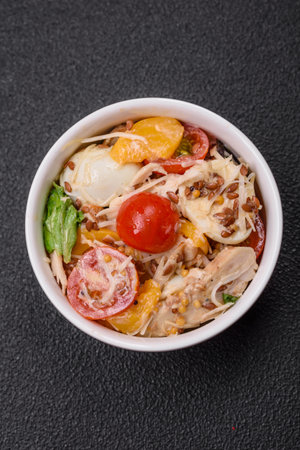 Delicious fresh salad with chicken, quail eggs, cherry tomatoes, lettuce, salt and spices on a dark concrete backgroundの写真素材