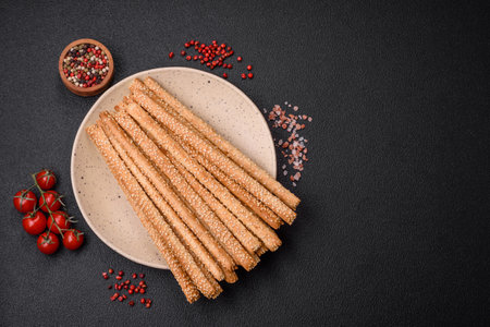 Delicious fresh grissini sticks with salt and sesame seeds on a dark concrete backgroundの写真素材