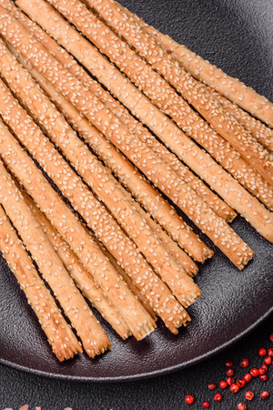 Delicious fresh grissini sticks with salt and sesame seeds on a dark concrete backgroundの写真素材