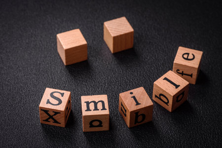 A concept consisting of the inscription of the word smile, with round emoticons on a dark concrete...