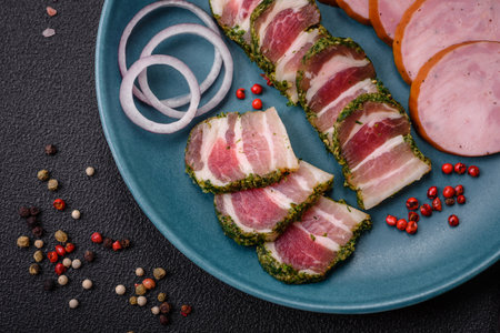 Delicious fresh bacon stripes with spices and salt on a dark concrete backgroundの写真素材