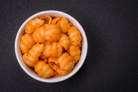 Delicious fresh pasta with pesto sauce, salt, spices and herbs on a ceramic plate on a textured...