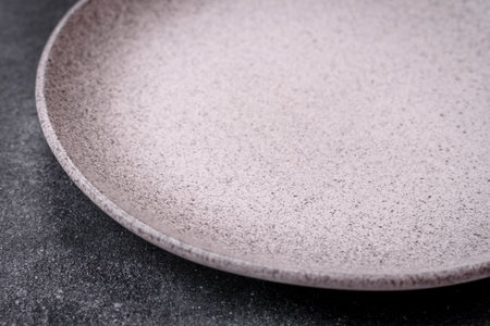 Empty round ceramic plate as an item of kitchen utensils on a textured concrete backgroundの写真素材