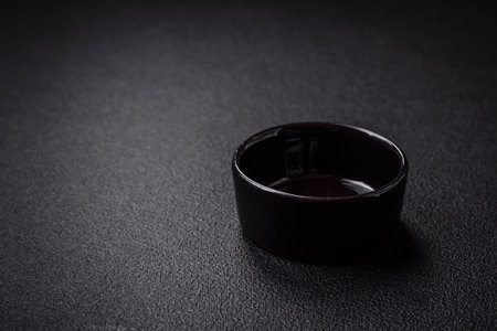 Beautiful empty black ceramic gravy boat on a textured concrete background. Kitchen utensil item