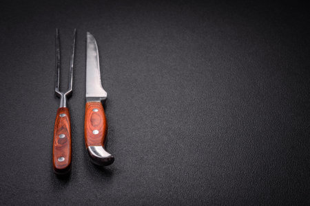 Kitchen knife and fork made of steel with copy space on a dark concrete backgroundの写真素材
