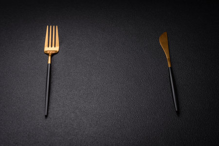 Kitchen knife and fork made of steel with copy space on a dark concrete backgroundの写真素材