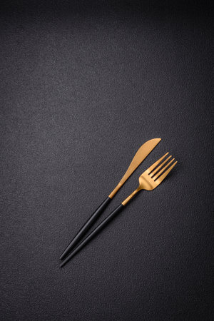 Kitchen knife and fork made of steel with copy space on a dark concrete backgroundの写真素材