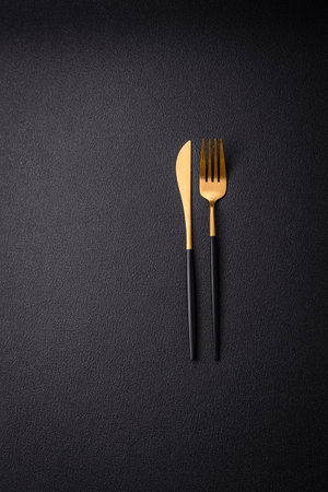 Kitchen knife and fork made of steel with copy space on a dark concrete backgroundの写真素材