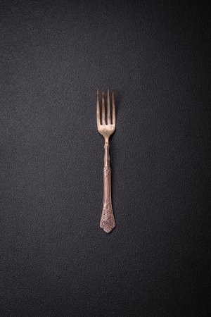 Kitchen fork made of steel on a dark textured background. Kitchen utensils on the tableの写真素材