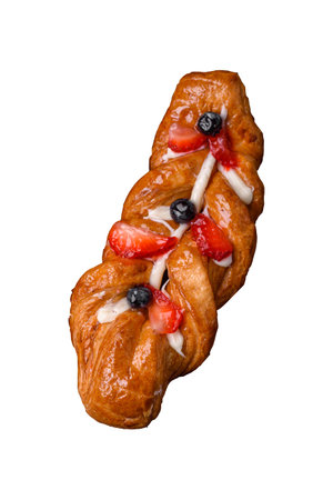Delicious fresh crispy pastry in the form of a pigtail with strawberries and blueberries on a dark...