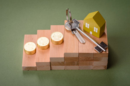 A small wooden house and keys as an idea for investing in your own home and achieving the goal of...