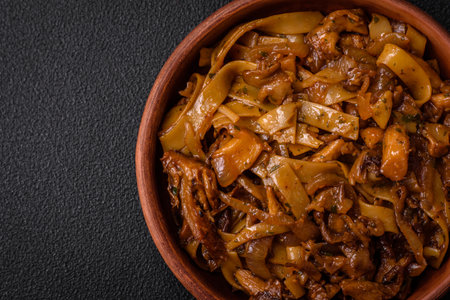 Delicious asian udon dish with vegetables, mushrooms, salt and spices on a ceramic plate on a dark concrete backgroundの写真素材