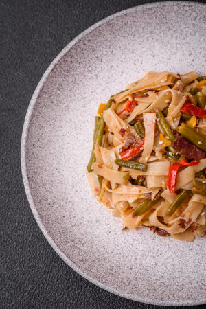 Delicious Asian dish udon with hot peppers, green beans, spices and herbs on a ceramic plate on a dark concrete backgroundの写真素材