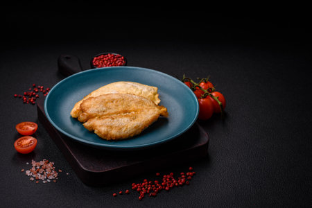 Delicious battered chicken breast chops with salt, spices and herbs on a dark concrete background