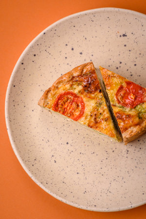 Delicious quiche with tomato, cheese, chicken, spices and herbs on a dark concrete background