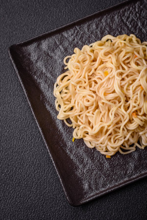 Delicious Asian cuisine dish with rice noodles, peppers, mushrooms and spices on a dark concrete backgroundの写真素材
