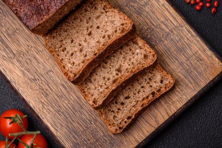 Delicious fresh crispy brown bread with seeds and grains on a dark concrete backgroundの写真素材