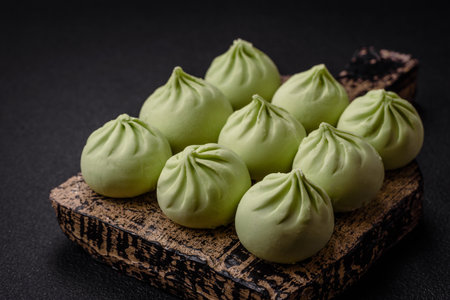 Raw khinkali or green dumplings with salt, spices and herbs on a dark concrete background