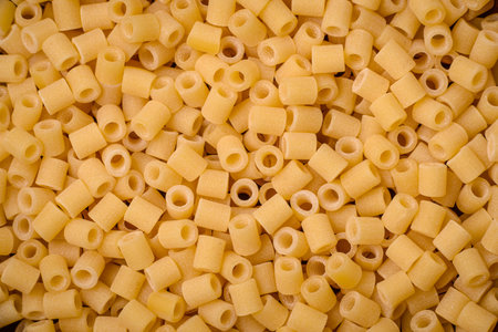 Raw ditali pasta made from durum wheat on a dark concrete background. Preparing a delicious,...