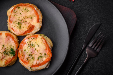 Delicious baked fish fillet with cheese, tomatoes, salt, spices and herbs on a dark concrete...