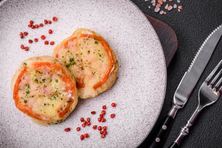 Delicious baked fish fillet with cheese, tomatoes, salt, spices and herbs on a dark concrete backgroundの写真素材