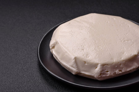 Delicious fresh white young cheese from cow's or sheep's milk on a dark concrete background
