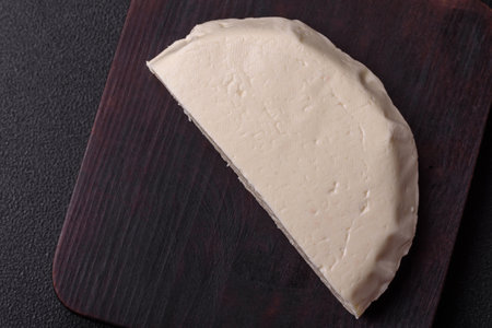 Delicious fresh white young cheese from cow's or sheep's milk on a dark concrete background