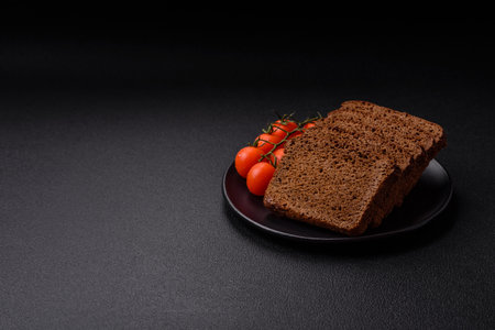 Delicious brown bread with seeds and grains cut into slices on a textured concrete background