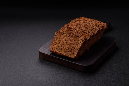 Delicious brown bread with seeds and grains cut into slices on a textured concrete background