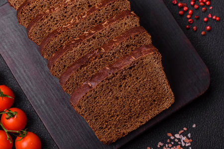 Delicious brown bread with seeds and grains cut into slices on a textured concrete background