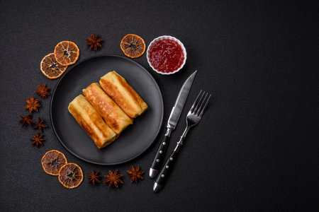 Delicious fried pancakes with filling rolled on a dark concrete background. Delicious nutritious...