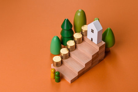 Conceptual composition of wooden steps with coins, model of a house as the growth of financial investments in real estateの写真素材