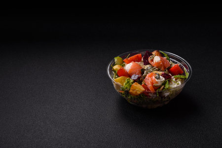 Delicious juicy salad with salmon, tomatoes, cucumber, herbs, pumpkin seeds, salt and spices in a ceramic plate on a dark concrete backgroundの写真素材