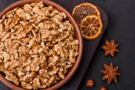Delicious fresh peeled raw walnuts in a ceramic plate on a dark concrete background