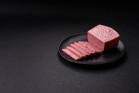 Delicious canned pink ham with salt, spices and herbs on a dark concrete backgroundの写真素材