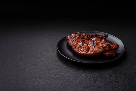 Fresh juicy delicious beef steak on a dark background. Meat dish with spices and herbsの写真素材