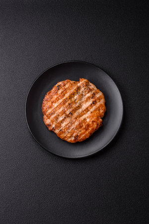 Delicious fresh grilled chicken fillet with spices and herbs on a dark concrete background. A dish cooked over fireの写真素材