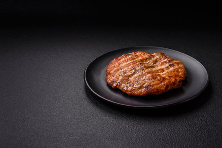 Delicious fresh grilled chicken fillet with spices and herbs on a dark concrete background. A dish cooked over fireの写真素材