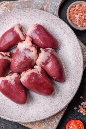 Raw turkey or chicken hearts with salt and spices on a dark concrete backgroundの写真素材