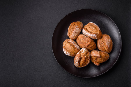 Fresh baked bread buns with salt, spices, seeds and grains on a dark background